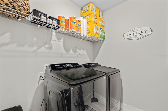 clothes washing area with laundry area, baseboards, and separate washer and dryer