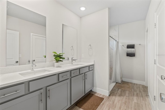 bathroom featuring a sink, a shower with curtain, double vanity, and wood finished floors