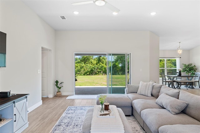 living room featuring recessed lighting, baseboards, light wood-style flooring, and ceiling fan with notable chandelier
