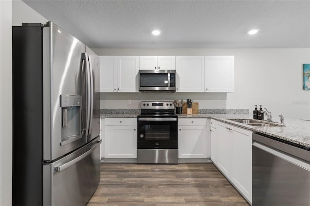 kitchen with a sink, dark wood finished floors, appliances with stainless steel finishes, and white cabinets