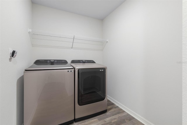 laundry room with laundry area, baseboards, wood finished floors, and separate washer and dryer