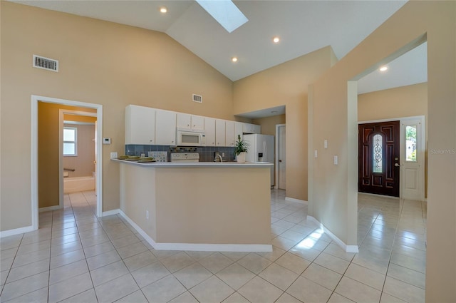 kitchen with visible vents, a skylight, light tile patterned floors, white cabinets, and white appliances