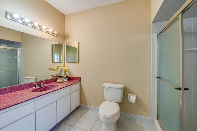 bathroom with tile patterned floors, baseboards, vanity, toilet, and tiled shower