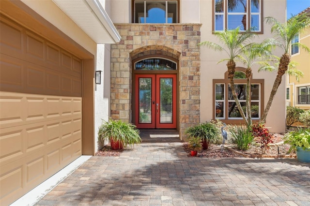 114 Emerald Lake Dr, Palm Coast, FL 32137 - property entrance featuring a garage, stucco siding, french doors, and stone siding