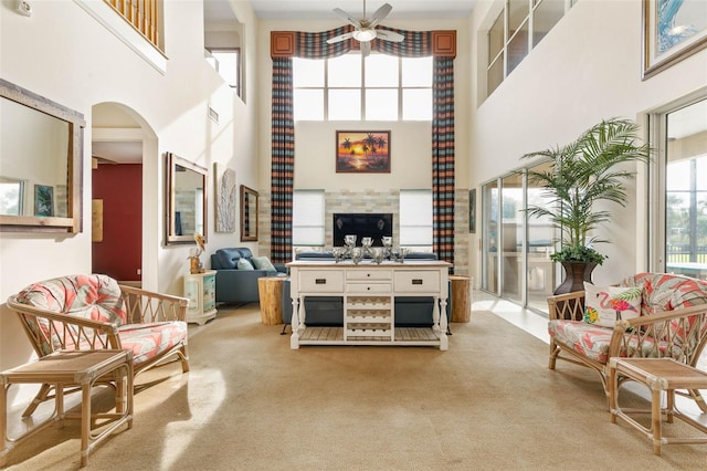 114 Emerald Lake Dr, Palm Coast, FL 32137 - living area featuring a fireplace, ceiling fan, a high ceiling, light colored carpet, and arched walkways