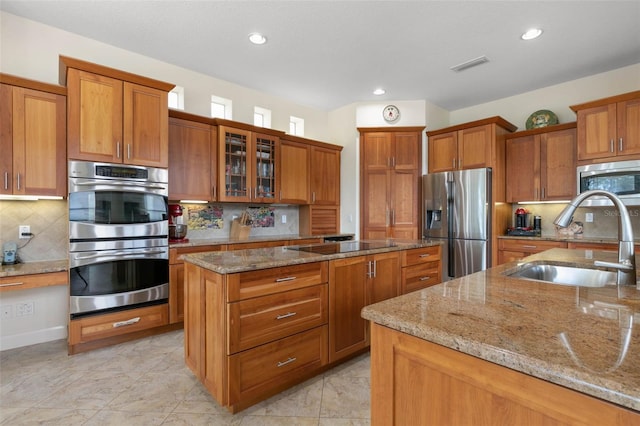 114 Emerald Lake Dr, Palm Coast, FL 32137 - kitchen featuring a center island, a sink, brown cabinets, and stainless steel appliances