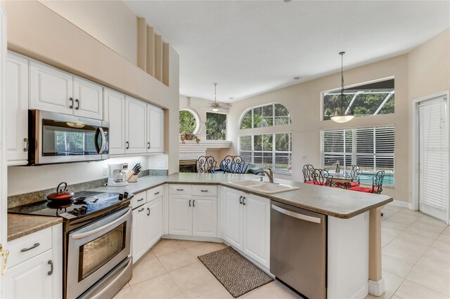 69 Coquina Ridge Way, Ormond Beach, FL 32174 - kitchen with white cabinets, light tile patterned flooring, a sink, stainless steel appliances, and a peninsula