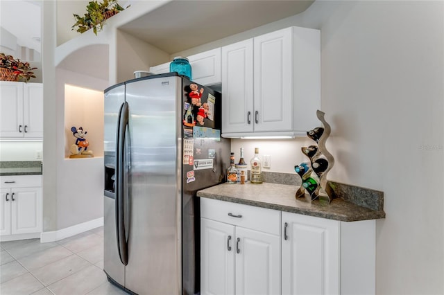 69 Coquina Ridge Way, Ormond Beach, FL 32174 - kitchen with white cabinets, light tile patterned flooring, dark countertops, and stainless steel fridge