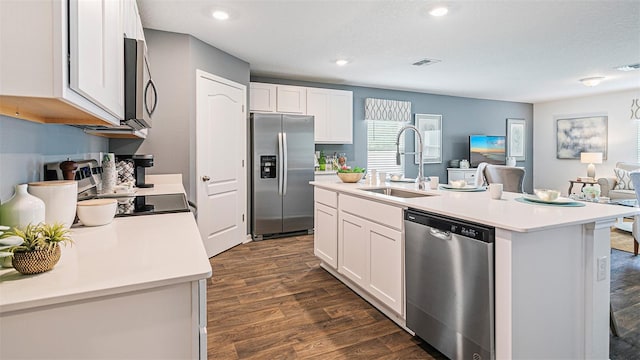 kitchen featuring a sink, light countertops, stainless steel appliances, open floor plan, and dark wood-type flooring