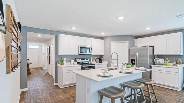 kitchen with a sink, a breakfast bar area, stainless steel appliances, and dark wood finished floors