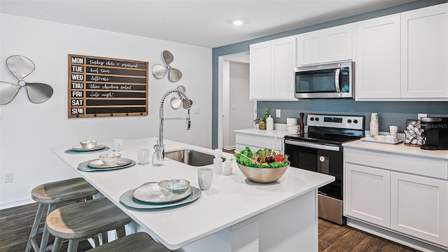 kitchen with light countertops, stainless steel microwave, a kitchen bar, and range with electric cooktop
