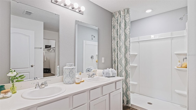 full bathroom with double vanity, visible vents, a sink, and a stall shower