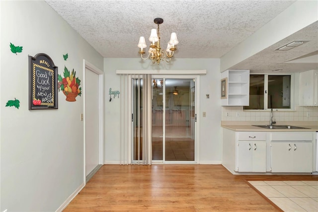 8720 SW 108th Ln, Ocala, FL 34481 - unfurnished dining area featuring an inviting chandelier, a sink, a textured ceiling, baseboards, and light wood-type flooring