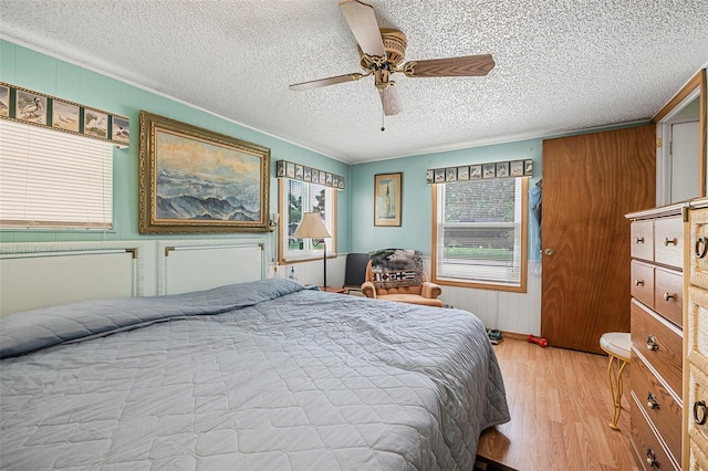 bedroom featuring a textured ceiling, ceiling fan, radiator heating unit, and light wood-style flooring