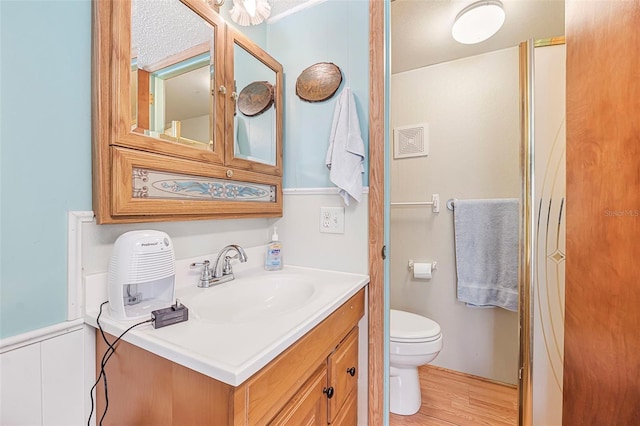 bathroom with toilet, wood finished floors, and vanity