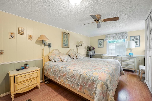 bedroom with a textured ceiling, ceiling fan, and wood finished floors