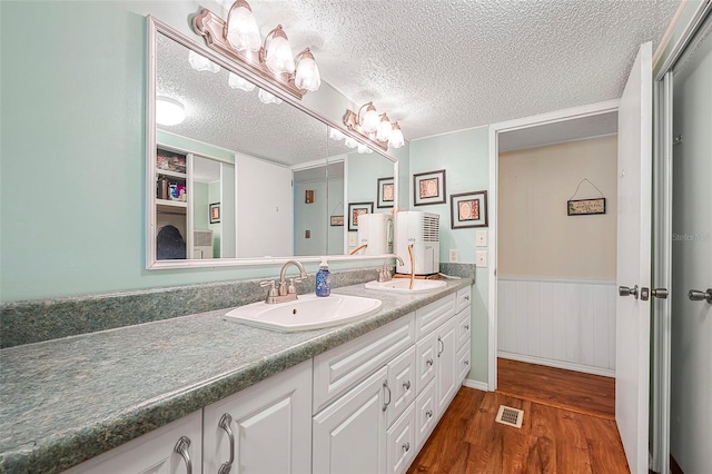 full bathroom with a sink, double vanity, wood finished floors, and visible vents