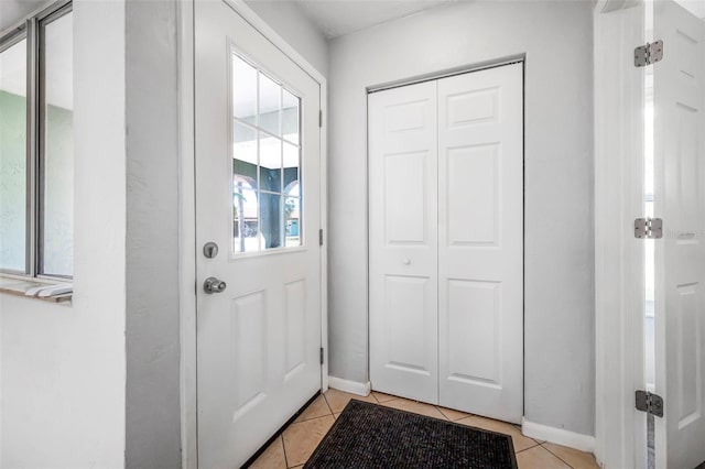 doorway to outside with baseboards and light tile patterned floors