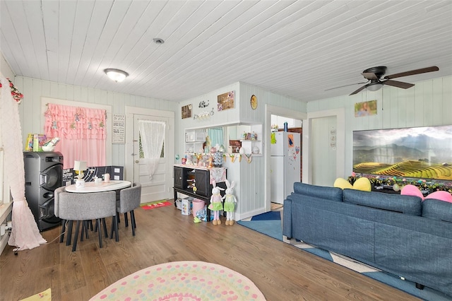 living area with wood walls, ceiling fan, wood finished floors, and wooden ceiling