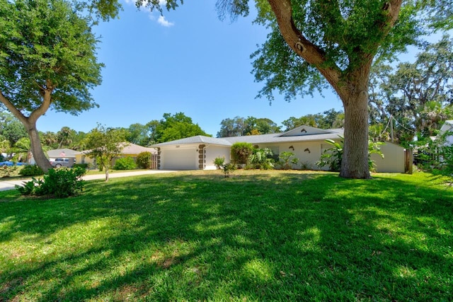 view of front of house with an attached garage, a front lawn, stucco siding, and concrete driveway