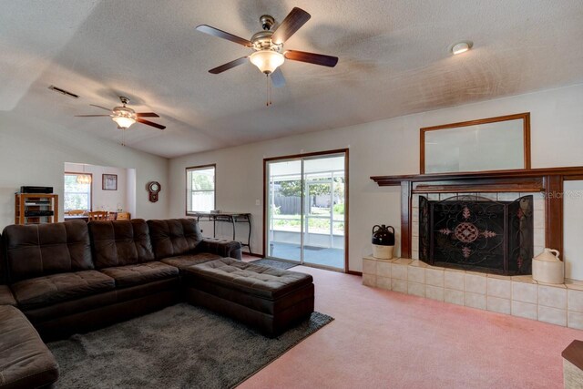 living room featuring a textured ceiling, a ceiling fan, carpet flooring, and a tile fireplace