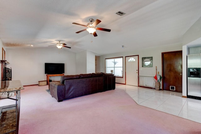 living area featuring visible vents, light carpet, baseboards, ceiling fan, and vaulted ceiling