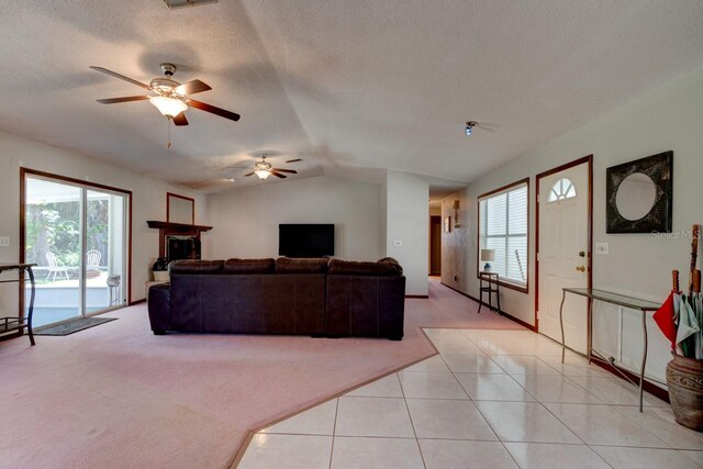 living room featuring ceiling fan, light carpet, vaulted ceiling, and a textured ceiling