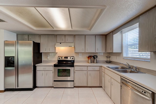 kitchen featuring a sink, light countertops, light tile patterned floors, under cabinet range hood, and stainless steel appliances