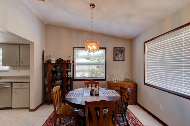 dining area with a textured ceiling, a chandelier, baseboards, light tile patterned floors, and vaulted ceiling