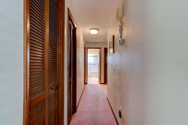 corridor with light carpet and a textured ceiling