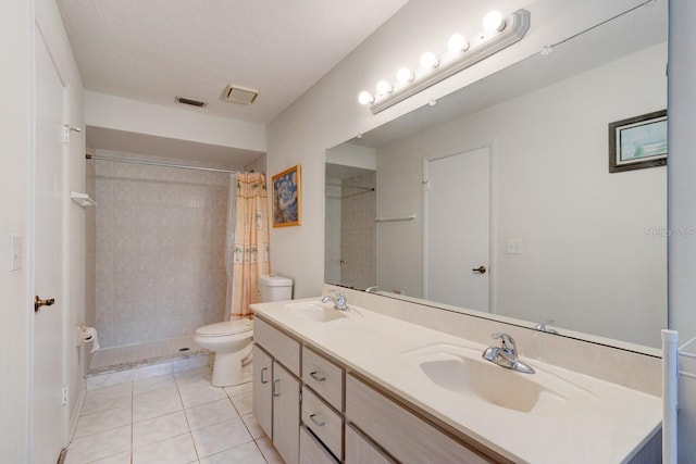 bathroom featuring toilet, visible vents, a tile shower, and a sink