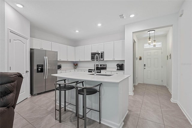 kitchen with a kitchen breakfast bar, appliances with stainless steel finishes, white cabinetry, light countertops, and light tile patterned flooring