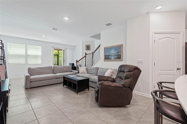 living area featuring visible vents, baseboards, light tile patterned floors, and stairway