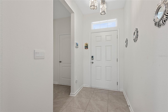 foyer entrance with light tile patterned flooring, baseboards, and an inviting chandelier