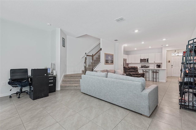 living area featuring visible vents, light tile patterned flooring, stairway, recessed lighting, and a chandelier