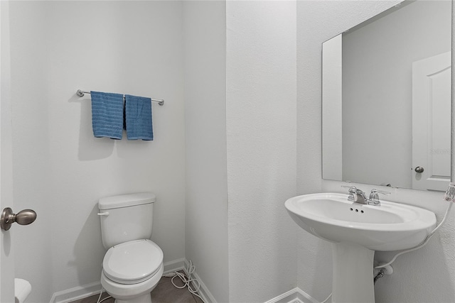 half bath with baseboards and toilet