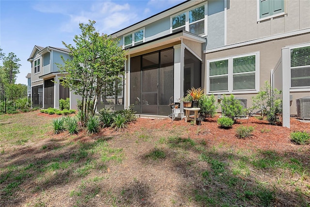 back of house featuring stucco siding, a sunroom, and cooling unit