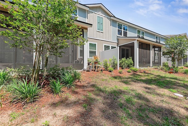 rear view of property with board and batten siding and a sunroom