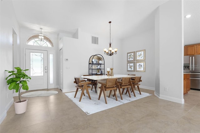 dining area featuring a chandelier, baseboards, visible vents, and a high ceiling
