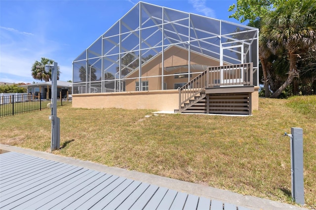 back of house featuring glass enclosure, a yard, fence, and stairway