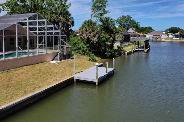 view of dock with a yard, a water view, and glass enclosure