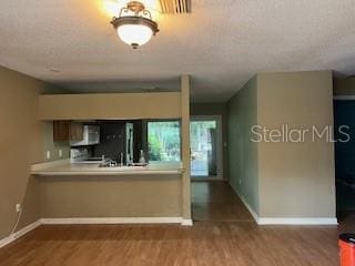 kitchen with wood finished floors, baseboards, and stainless steel microwave