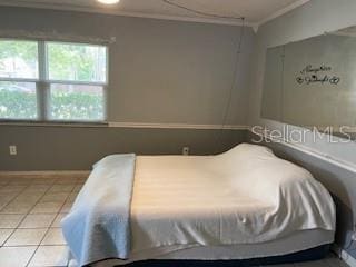 bedroom featuring crown molding, tile patterned flooring, and baseboards