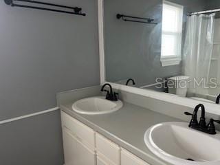 full bath featuring double vanity and a shower with shower curtain