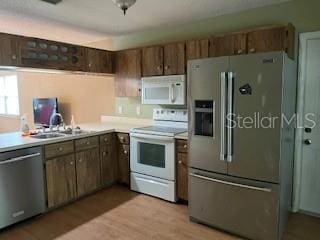 kitchen with appliances with stainless steel finishes, light countertops, and light wood-type flooring