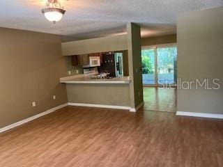 39 Bird Of Paradise Dr, Palm Coast, FL 32137 - kitchen featuring fridge, wood finished floors, white microwave, light countertops, and a peninsula