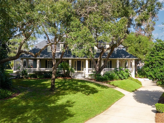 view of front of house with driveway, covered porch, a front lawn, and a shingled roof