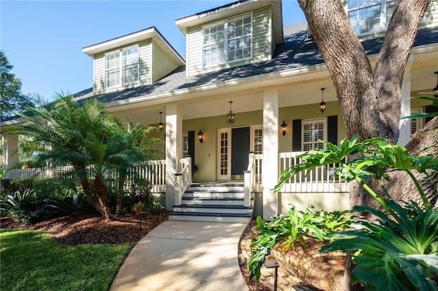 view of front of home featuring covered porch, stucco siding, and roof with shingles