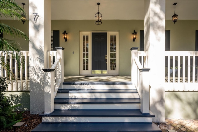 view of exterior entry featuring a porch and stucco siding