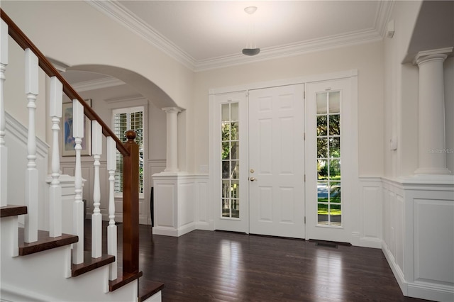 entryway with a decorative wall, healthy amount of natural light, crown molding, arched walkways, and dark wood-type flooring